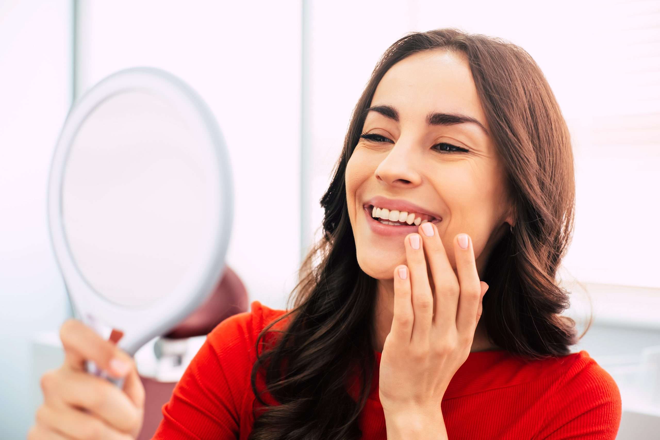 woman admiring her healthy teeth in a mirror at abington center with dr. dennis