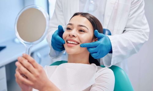 Dentist, mirror and woman check smile after teeth cleaning, braces and dental consultation. Healthcare, dentistry and happy female patient with orthodontist for oral hygiene, wellness and cleaning woman sitting in dental chair looking at her smile in a mirror. her teeth are back to normal after emergency dental care with abington center in clarks summit