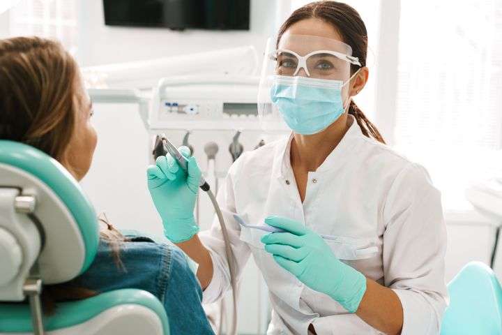 Female dentist smiling at camera while preparing to examine smiling patient in dental chair at Clarks Summit practice